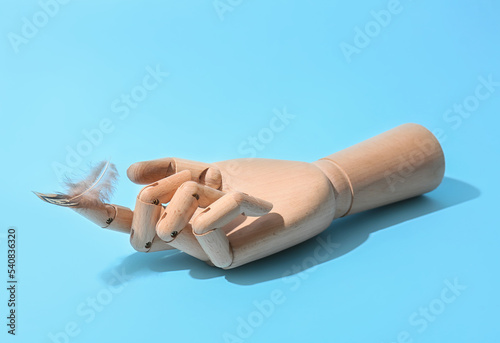 Wooden hand with feather on...