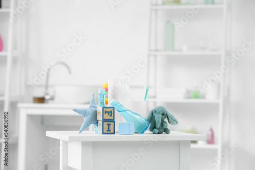Bath accessories for children and different toys on white table in light bathroom