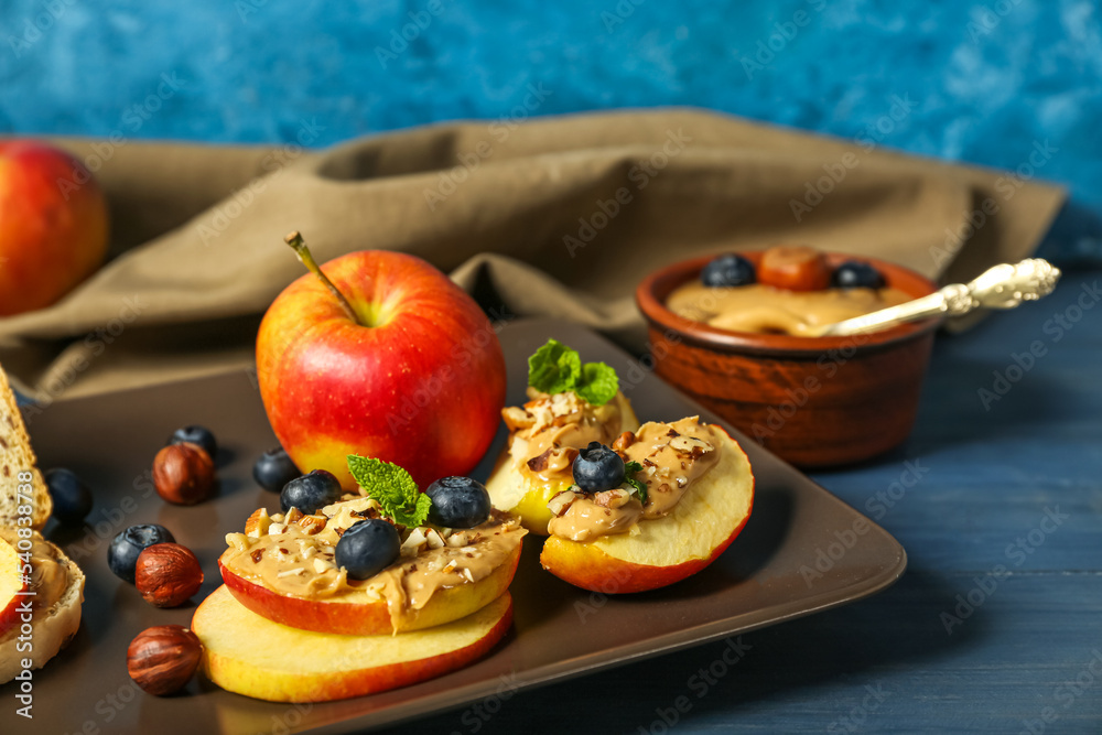 Plate of fresh apples with nut butter and blueberry on color wooden table, closeup