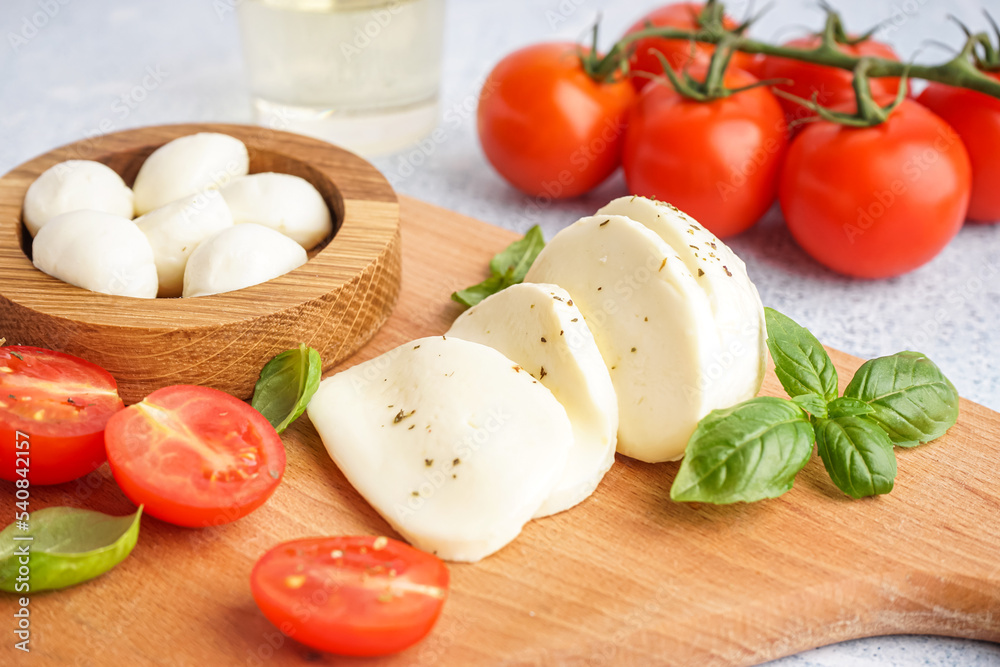 Wooden board with tasty mozzarella cheese on table, closeup