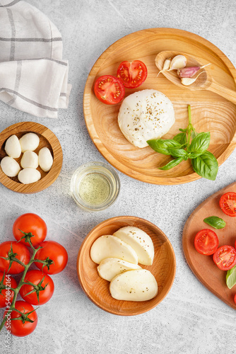 Composition with tasty mozzarella cheese and fresh tomatoes on light background