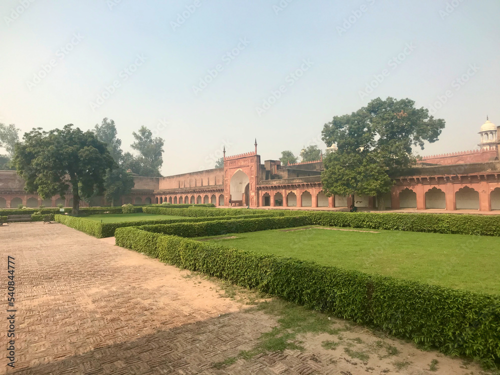 Agra, India, November 2019 - A large brick building with grass and trees Agra, India, November 2019 - A large brick building with grass and trees