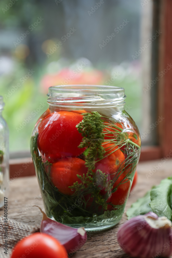 Glass jar with vegetables, herbs and brine on wooden table indoors Glass jar with vegetables, herbs and brine on wooden table indoors