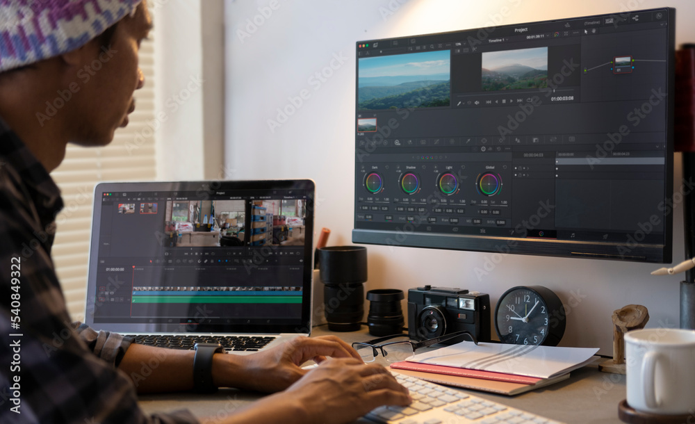 Fototapeta premium Male videographer editing video footage on professional computer at her workstation.