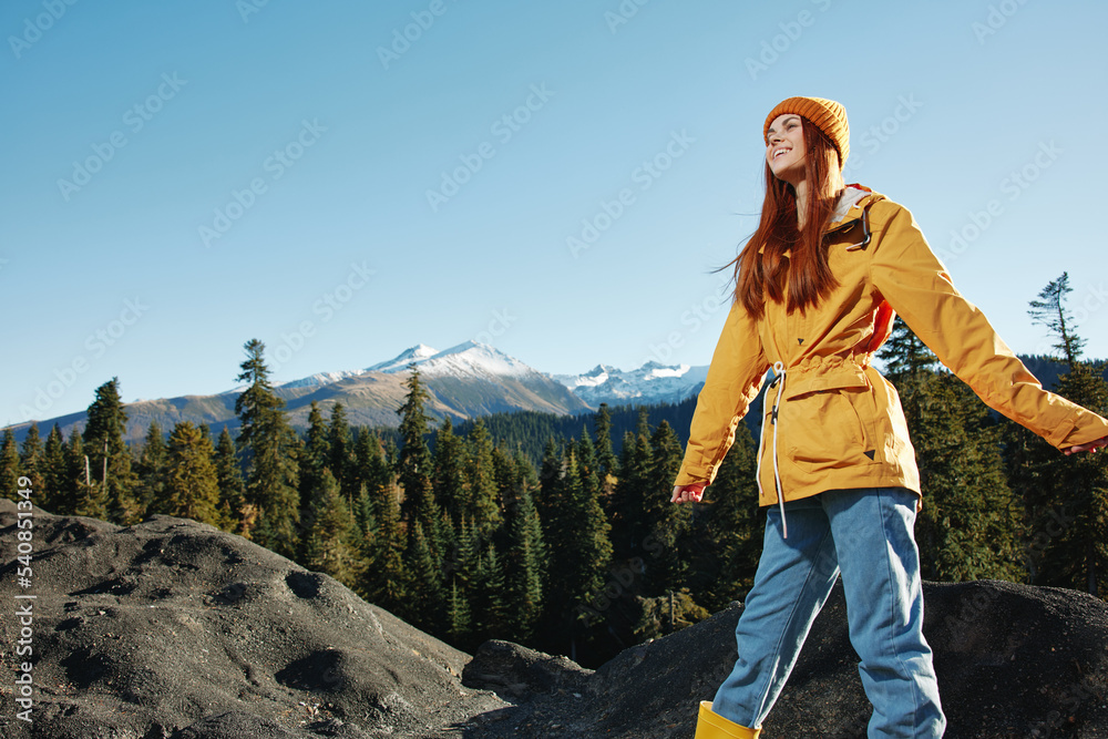 Naklejka premium Woman smile with teeth happiness and laughter hiker in yellow raincoat put her hands up and jumping trip in the fall and hiking in the mountains in the sunset freedom