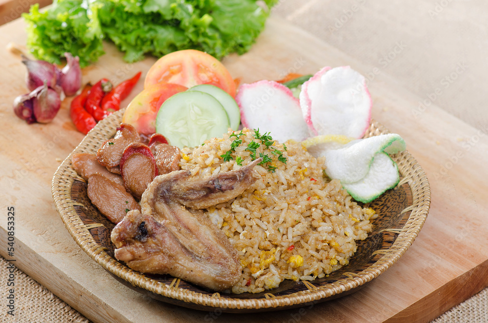 delicious asia, Indonesian food, spicy fried rice with fried chicken, several slice tomato and cucumber as a garnish, and kerupuk delicious asia, Indonesian food, spicy fried rice with fried chicken, several slice tomato and cucumber as a garnish, and kerupuk