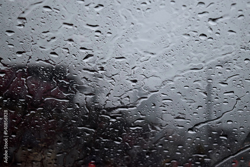 Raindrops on the windshield of the car. Raindrops form an abstract illustration on a car window. Driving a car in the rain