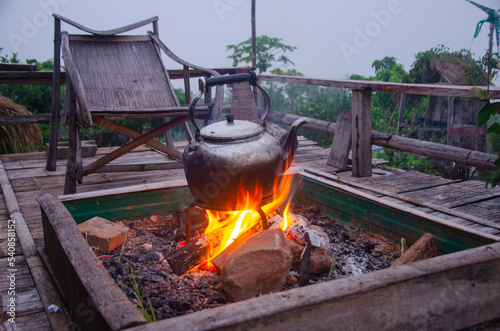 Fototapeta Naklejka Na Ścianę i Meble -  Old black kettle in stand on hot fire in outdoor terrce protection