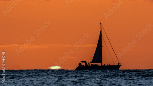 Incredible sunset on Waikiki Beach with sail boat silhouette. Sunset sailing in Hawaii. 