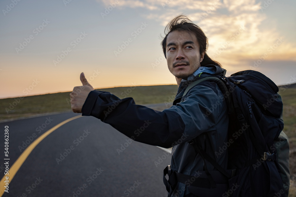 Mid adult man hitchhiking on the road Mid adult man hitchhiking on the road