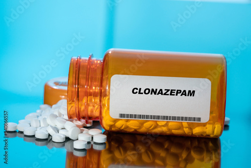 Clonazepam white medical pills and tablets spilling out of a drug bottle. Macro top down view with copy space. photo