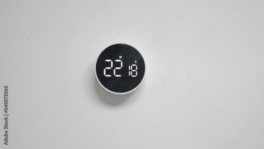 Wall electronic black white clock with minimalistic design, with reverse time response, hanging on a white wall with copy space for advertising text. Timer. Chronometer. The countdown has started.
