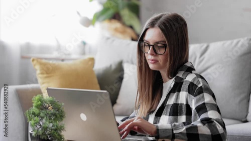 Young woman sitting on floor using laptop. Caucasian female working on computer, typing corporate message, communicating with clients. Girl student doing homework university assignment on laptop.