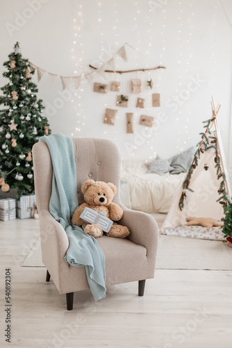 New year 2023 scandinavian interior. children's tent decorated with spruce branches, cozy armchair and Christmas tree decorated in beige natural colors. Advent calendar on the wall. selective focus