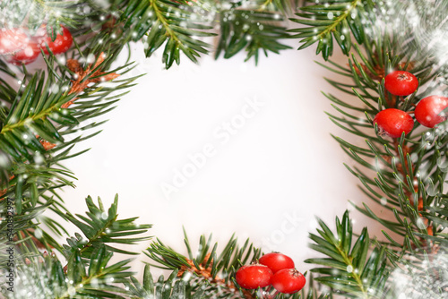  White paper square shaped sheet with fir spruce branches and red berries. Christmas New Year background. Greeting card. Minimal, nature, eco concept. Mockup, space for text.