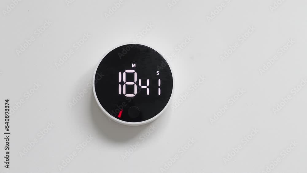 Wall electronic black white clock with minimalistic design, with reverse time response, hanging on a white wall with copy space for advertising text. Timer. Chronometer. The countdown has started.