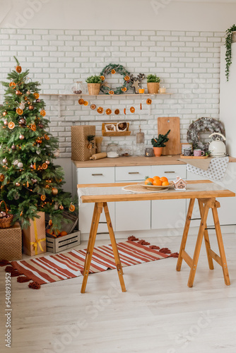New year 2023 American kitchen interior. Christmas tree decorated with pieces of dried oranges  Wreath above the table  natural colors  organic living. selective focus