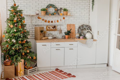 New year 2023 American kitchen interior. Christmas tree decorated with pieces of dried oranges, Wreath above the table, natural colors, organic living. selective focus