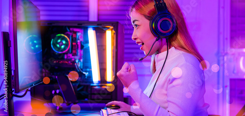 Winning Victory. Asian gamer playing online video game excited on desktop computer PC colorful neon LED lights, young woman in gaming headphones using computer she happy successful, E-Sport concept