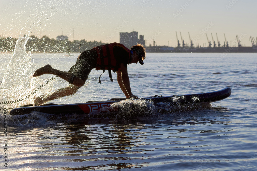 Fototapeta premium Man doing beach start on SUP on rowing competitions from stand up paddle boarding. River beach start on SUP