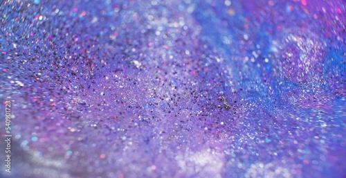 Blur glitter background. Sequin texture. Galaxy stardust. Defocused iridescent purple blue pink silver color shimmering circles surface.
