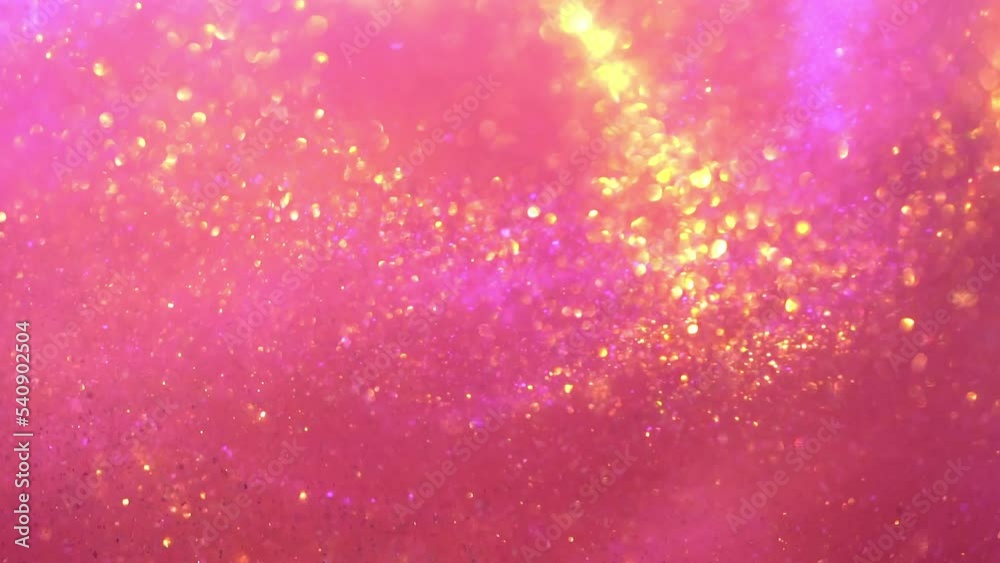 Wavy movement of flying gold particles on a pink background. Chaotically moving gold shiny dust particles and bokeh. Beautiful abstract moving background.