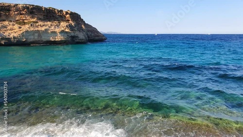 View of turquoise crystal clear sea with swinging waves and rocky coast in Mallorca island, Spain.