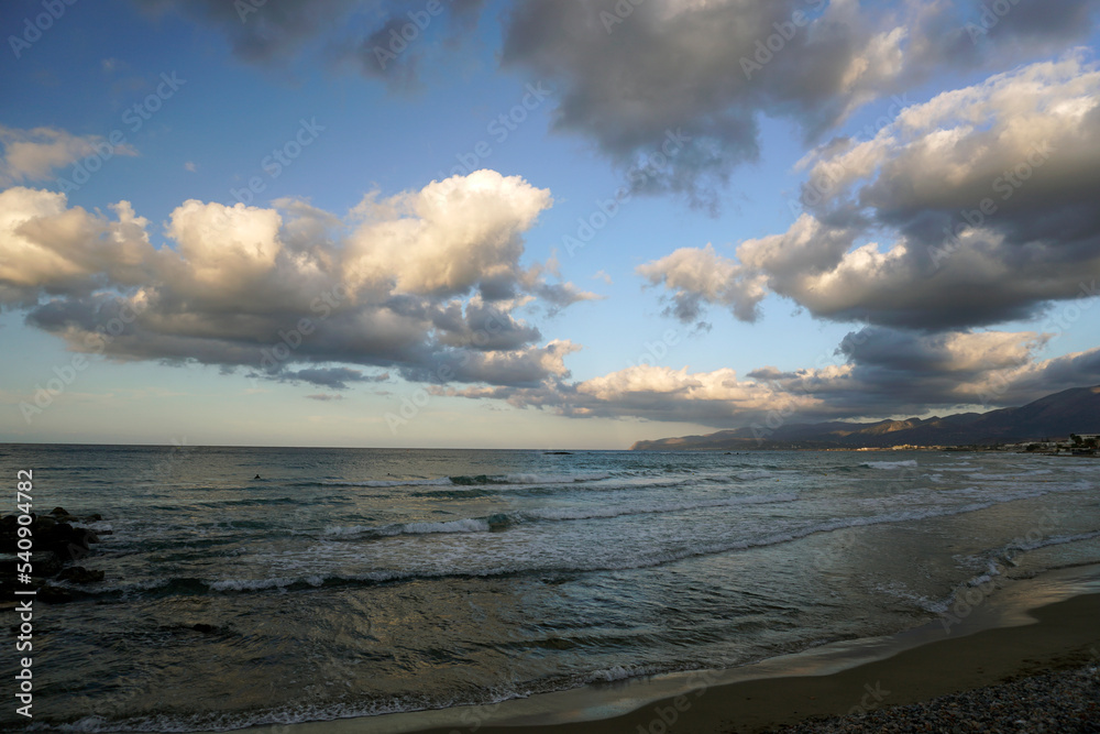 Evening on the shores of the Aegean Sea. Mid October. The magic of nature. The island of Crete. Bright light and low beautiful clouds in the rays of the setting sun.