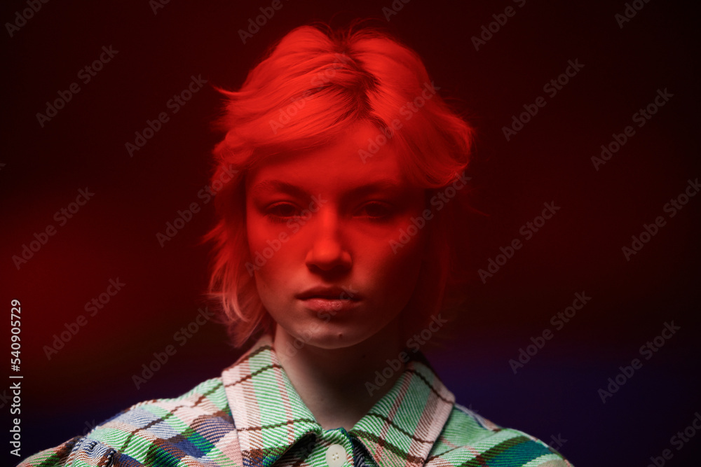 © Clique Images - Portrait of teenage girl with pink hair looking at camera with red light on her face © Clique Images - Portrait of teenage girl with pink hair looking at camera with red light on her face