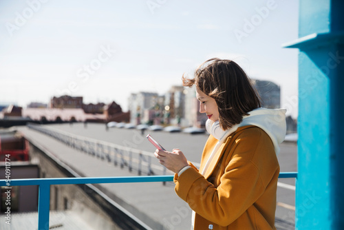 a woman in a yellow coat uses a mobile phone and walks around the city. copy space. 