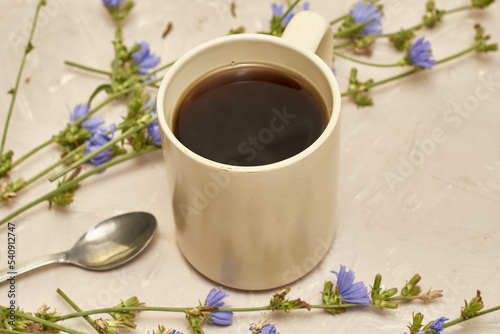 chicory drink in a coffee mug and a spoon next to chicory flowers