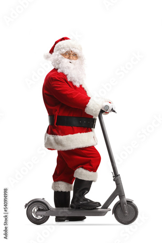 Full length profile shot of Santa Claus posing with an electric scooter