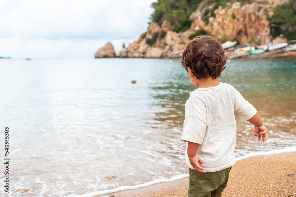 A boy throwing stones on the beach of the port of Sant Miquel, Ibiza Island. Balearic Islands A boy throwing stones on the beach of the port of Sant Miquel, Ibiza Island. Balearic Islands