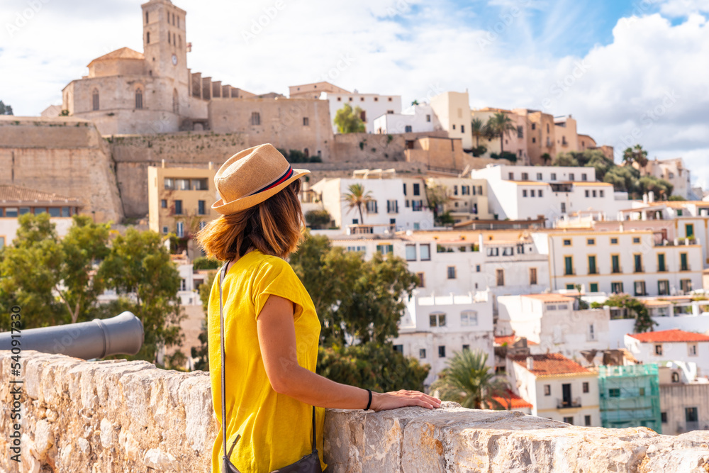A young woman tourist looking at the cathedral of Santa Maria de la Neu from the castle wall of Ibiza, Balearic Islands, Eivissa