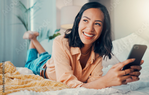 Happy woman, funny social media phone and thinking of online dating profile notification in bedroom in Spain. Young smile female relax at home, smartphone connection and 5g mobile network technology photo