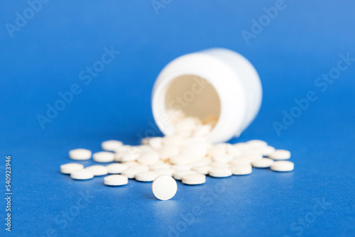 Medicine bottle and white pills spilled on a light background. Medicines and prescription pills flat lay background. White medical pills and tablets spilling out of a drug bottle