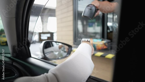 Beautiful woman pay for food or drinks via smart watch using barcode reader scanning barcode by driving through or drive thru. Contactless payment. photo