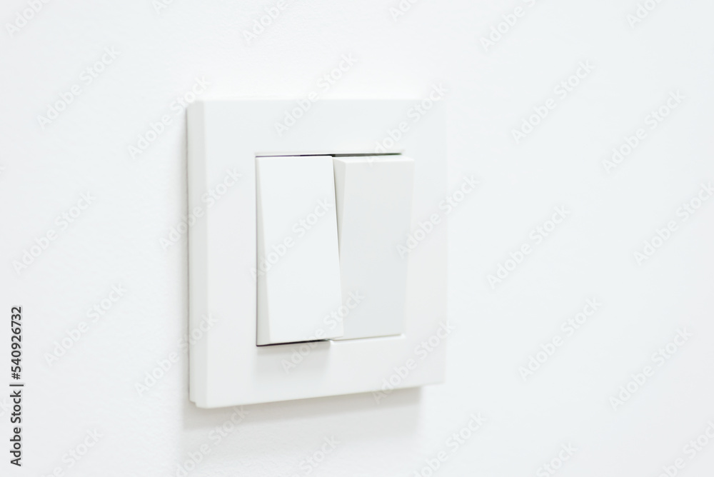 White light switch on white wall. One part of switch is turned on, the other is turned off White light switch on white wall. One part of switch is turned on, the other is turned off
