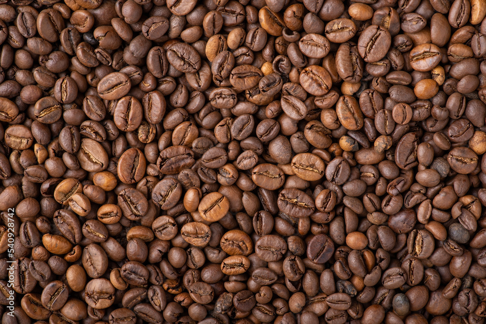Top-down background of roasted coffee beans. Golden aromatic coffee beans background
