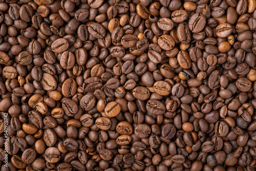 Top-down background of roasted coffee beans. Golden aromatic coffee beans background