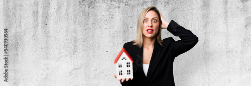 pretty blonde woman feeling stressed, anxious or scared, with hands on head. real state concept