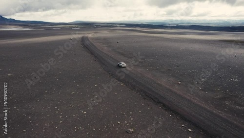 Drone following a silver car with the camera tilting up slowly driving offroad in the moonlike backcountry of Iceland 4k photo