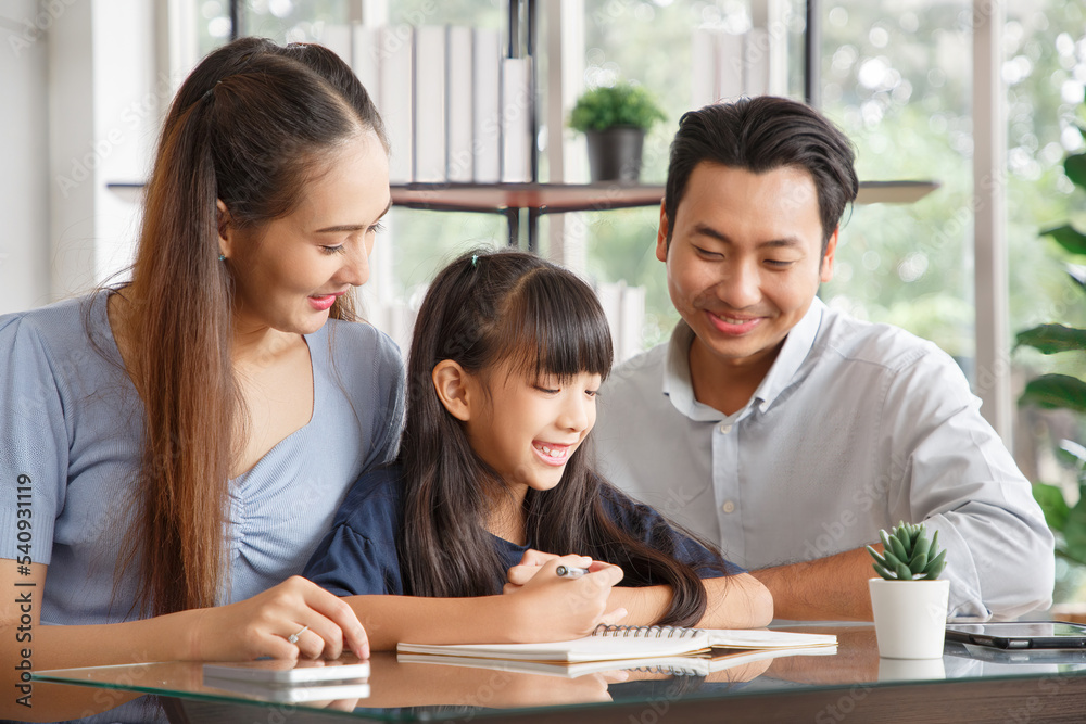 Children education and home school concept : Young asian father and mother see little daughters' study. Excited smiling small child girl enjoying learning and writing with pleasant dad and mom at home Children education and home school concept : Young asian father and mother see little daughters' study. Excited smiling small child girl enjoying learning and writing with pleasant dad and mom at home