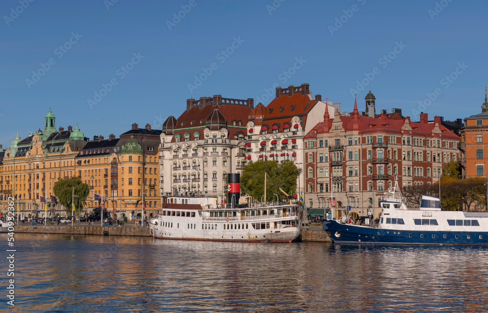 Tourists, offices, apartment and hotel buildings, old steam and modern boats a colorful autumn day in Stockholm