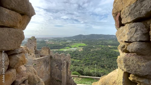 Tourism medieval ruined castle in Spain seen from a rock window towards the rest of the castle with a cultivated field in the background photo