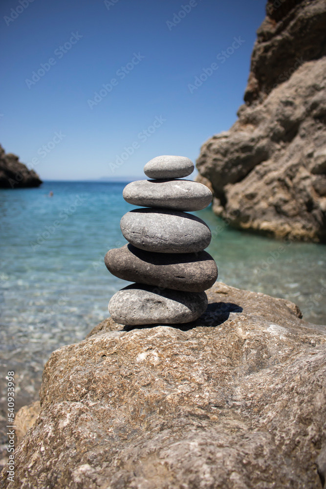 Balanced pebble pyramid silhouette on the beach. exotic sea on the background. Zen stones on the sea beach, meditation, spa, harmony, calmness, balance concept Selective focus, sea rocks Balanced pebble pyramid silhouette on the beach. exotic sea on the background. Zen stones on the sea beach, meditation, spa, harmony, calmness, balance concept Selective focus, sea rocks