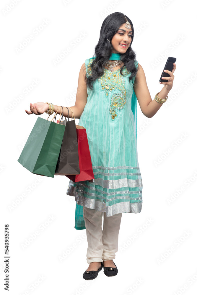 Indian woman carrying shopping bags while holding mobile phone