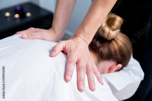 Masseuse making a back massage to a young woman at the  spa.
