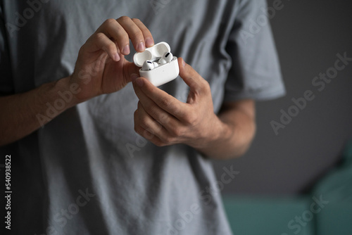 Φωτογραφία hands holding wireless white earphones opened case