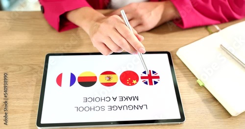 Woman hand uses tablet with her fingers and an app is popular free platform for learning languages photo
